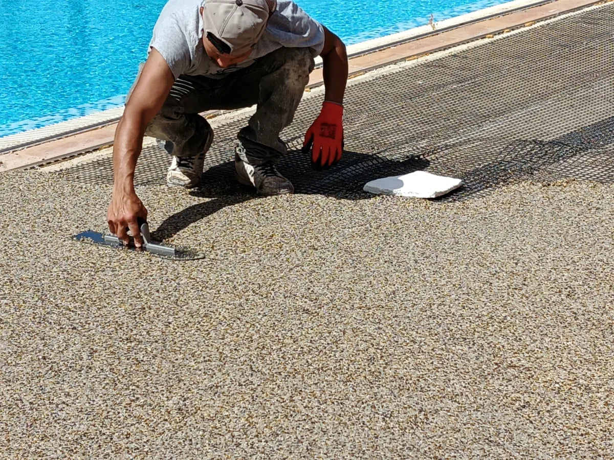 Craftsperson hand-trowelling a resin-bound pool surface